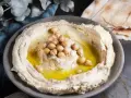 Krämig hummus med kikärtor och olivolja, perfekt för ett enkelt hummus recept. Serveras med pitabröd.