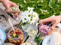 En härlig sommarmåltid med inlagd sill, hackad rödlök och vitt vin till sillen. Blommor och grönska i bakgrunden.