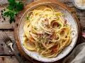 En tallrik krämig spaghetti carbonara, ett klassiskt pasta recept, toppad med parmesan och persilja.