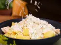 En krämig lax pasta med crème fraîche toppas med riven ost.