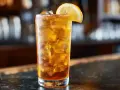 Ett glas Long Island Iced Tea med is och en citronskiva, redo att avnjutas vid en bar.