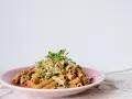 En läcker vegetarisk pasta med broccoli, valnötter och färska örter på en rosa tallrik.