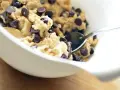 En skål med ljuvlig cookie dough med chokladbitar, redo för ett enkelt cookie dough recept. En sked vilar i smeten.