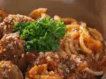 En skål med läckra polpette al sugo, köttbullar i tomatsås, serverade med pasta och toppade med färsk persilja och parmesan.