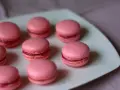 Rosa macarons med hallonfyllning på en vit tallrik. Perfekt för ett macarons recept.