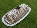 En läcker Budapestrulle med choklad och grädde, dekorerad med chokladrosor och pudersocker. Perfekt för ett sommarfika!