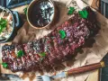 Saftiga spareribs i ugn, glaserade och serverade med en skål coleslaw och BBQ-sås. Perfekt för en festmåltid!