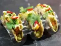 Tre läckra asiatiska tacos med koriander, chili och majs i en taco-hållare.