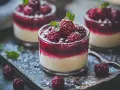 Tre glas med krämig panna cotta toppad med hallon och mynta, pudrad med florsocker.