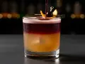 En vackert lagerdelad New York Sour med en körsbärs- och apelsinskalgarnering.