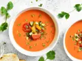 Två skålar med uppfriskande gazpacho, toppad med färska grönsaker. Ett perfekt gazpacho recept för varma dagar.