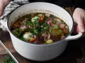 En gryta med mustig coq au vin, fylld med möra kycklingbitar, champinjoner, lök och morötter, toppad med färsk persilja.