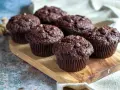 Fem saftiga chokladmuffins med chokladknappar på en träbricka. Perfekt för ett chokladmuffins recept.