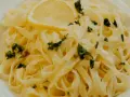 En portion krämig citronpasta med färsk persilja och en citronskiva. Perfekt till ett glas vitt vin.