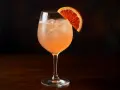 En uppfriskande paloma drink med is och en apelsinskiva som garnering, serverad i ett elegant glas.