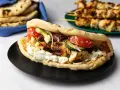 En saftig gyros med grillspett, tzatziki, tomat, gurka och oliver i pitabröd. Perfekt för ett snabbt grillspett recept.