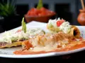 Enchiladas och en tostad med ost, guacamole och kött. En härlig tallrik med mexikansk mat som ser utsökt ut.
