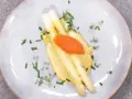 Vit sparris med krämig hollandaisesås, toppad med rom och garnerad med gräslök och örter. En klassisk och elegant rätt.