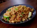 En tallrik med utsökt fried rice, garnerad med limeklyftor och salladslök.