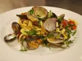 En tallrik med pasta vongole, där färska vongole-musslor blandas med tagliatelle, körsbärstomater och persilja.