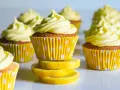 Gula citronmuffins med fluffig frosting, serverade i prickiga formar. Perfekt för ett citronmuffins recept!