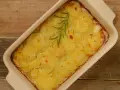 En ugnsform med gyllene, tunna potatisskivor, en klassisk pommes anna, toppad med en rosmarinkvist.