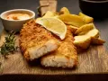 Krispigt panerad fisk med klyftpotatis och en citronskiva. Ett perfekt fisk recept för en god middag.