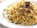 En tallrik med spaghetti toppad med rikligt med riven tryffel. Perfekt för en lyxig middag med ett gott vin till tryffelpasta.