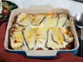 En ugnsform med en gyllene, bubblande moussaka, redo att serveras. Perfekt för ett mysigt middagsrecept.