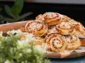 En hög med gyllene kanelbullar, redo att bakas enligt ett enkelt kanelbullar recept. En kavel ligger bredvid.