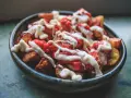 En skål med krispiga patatas bravas, toppade med en kryddig tomatsås och krämig aioli.