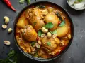 En skål med kyckling i krämig massaman curry, toppad med jordnötter och koriander. Ett läckert massaman curry recept.