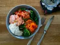 En härlig poke bowl med lax, broccoli, tomat, rivna morötter och en krämig sås. Perfekt för en hälsosam lunch.