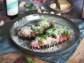 Halverade auberginer toppade med tomatsås, basilika och riven ost, redo att tillagas i ugnen. En härlig aubergine i ugn.