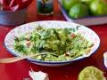 En skål med krämig guacamole, perfekt för ditt nästa guacamole recept. Serveras med tortillabröd, lime och chili.