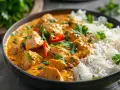 En skål med krämig kyckling curry med ris, toppad med färsk koriander och chili. En härlig måltid som värmer själen.