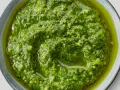 Närbild på hemmagjord pesto i en skål. Oljan flyter runt den gröna, grovhackade peston. Perfekt för att förlänga hållbarheten.