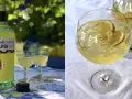 En flaska Limoncello Di Capri står bredvid två glas med den gyllene likören. Till höger syns två glas fyllda med is och citronskivor, redo att avnjutas som en uppfriskande limoncello spritz.