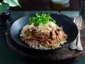 En tallrik med pulled pork med ris, toppad med krispig coleslaw och gröna blad. En härlig måltid som ser utsökt ut.