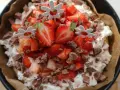 En läcker cheesecake med jordgubbar och chokladbitar, perfekt för ett somrigt cheesecake recept. Blomsterpinnar dekorerar toppen.