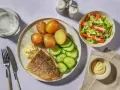En tallrik med stekt vit fisk, kokt potatis, gurka och en klick majonnäs. Ett perfekt vit fisk recept för en snabb middag.