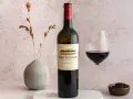 En flaska Rust en Vrede Estate vin, perfekt till oxfilé, står bredvid ett glas rött vin och en liten skål med pepparkorn.