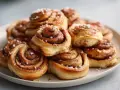 En hög med gyllene, nybakade glutenfria kanelbullar, toppade med pärlsocker. Perfekt för fikat!
