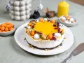 En vacker cheesecake med gul topping, dekorerad med påskägg och nötter. Perfekt för en härlig cheesecake påsk-firande.
