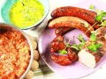 Grillad fläskfilé och korvar med en härlig bbq sås. Bredvid står en skål med en tomatröra och en grön sås.