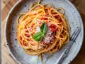 En tallrik med spaghetti och tomatsås, toppad med riven parmesan och en basilikakvist. Perfekt för en krämig burrata pasta.