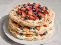 En flerskiktad marängtårta med grädde, bär och mandel. Perfekt som inspiration för ditt nästa tårtbotten recept.