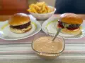 Två hamburgare med pommes frites och en skål med hemlagad hamburgerdressing. Perfekt för en mysig hemmakväll!