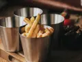 Friterade pommes i kastrull, serverade i små metallmuggar. En läcker aptitretare som påminner om hemgjord snabbmat.