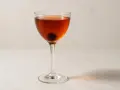 En klassisk manhattan drink med körsbär i ett elegant glas.